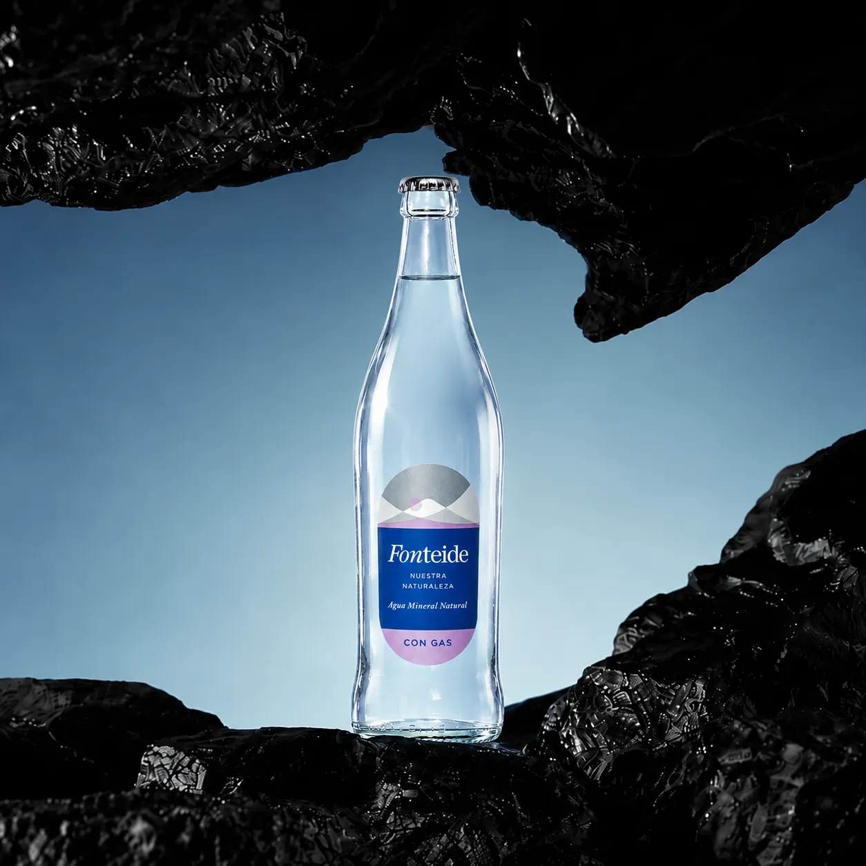 Botella de agua mineral natural Fonteide con gas en vidrio retornable entre rocas volcánicas