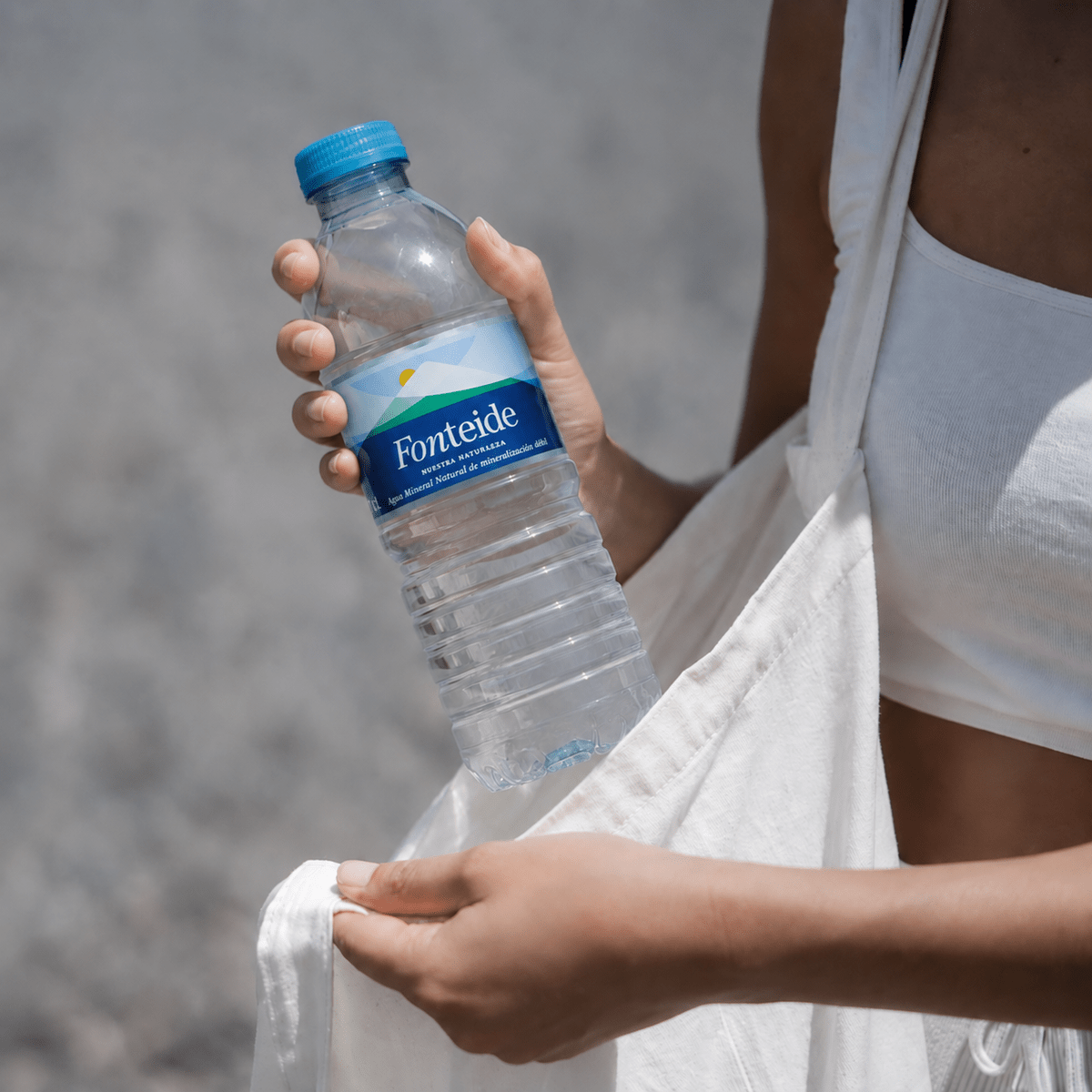 Mujer con una botella de agua mineral natural Fonteide en PET y una bolsa de tela